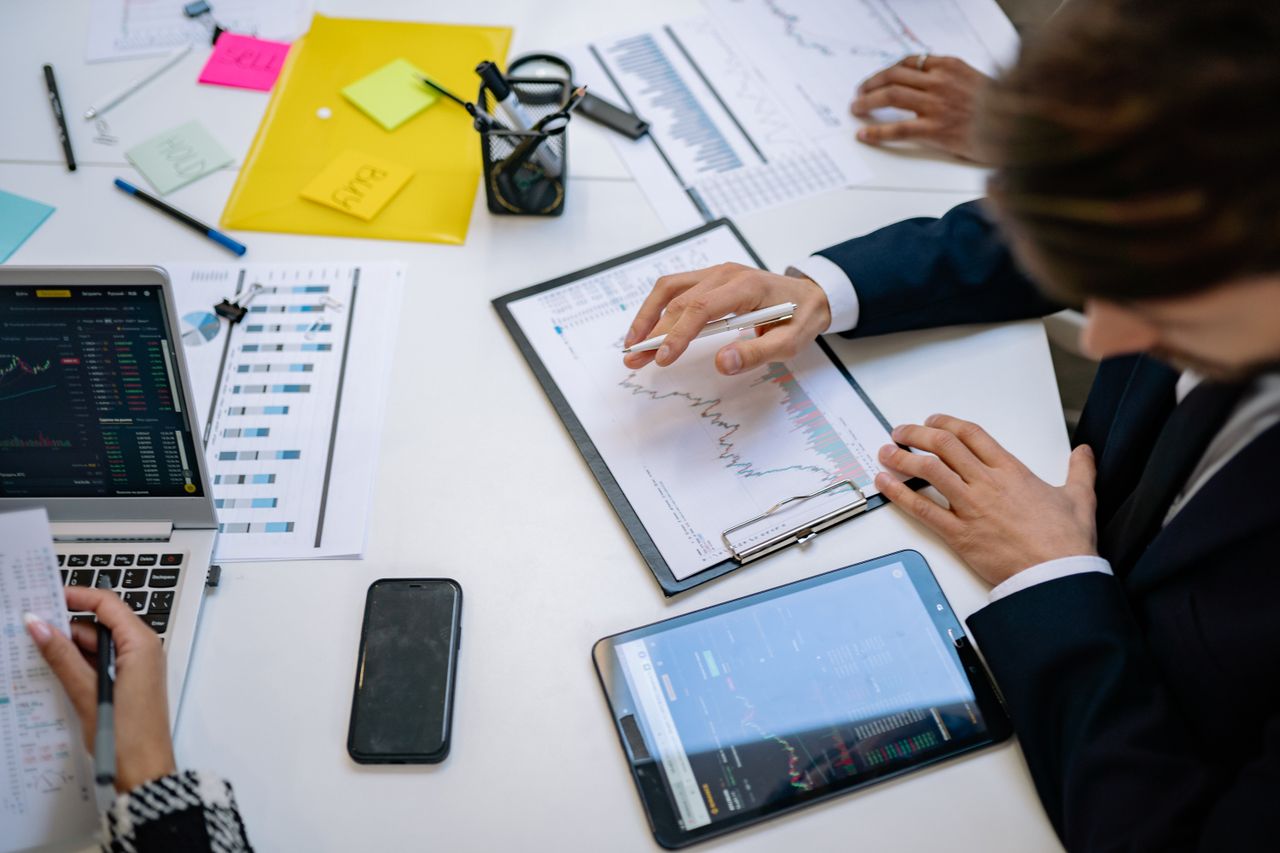 A team is examining financial charts and digital data on tablets in an office environment.