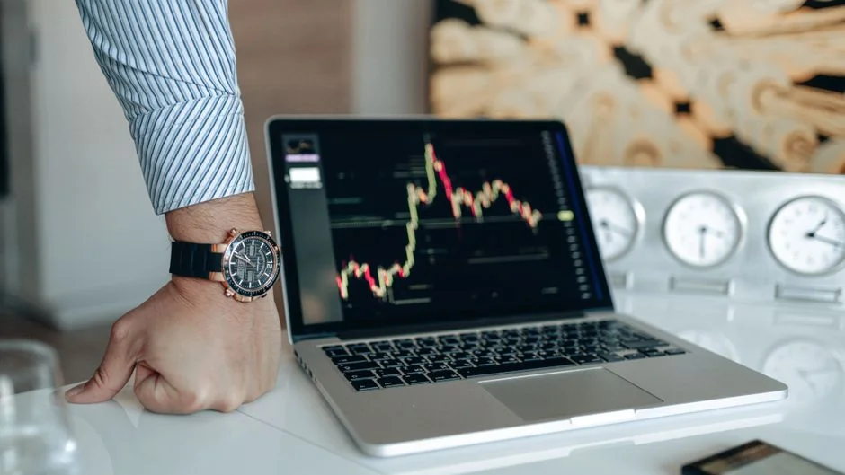 A hand holds a smartphone showing a BTC-USD chart amid digital trading screens, emphasizing crypto finance.